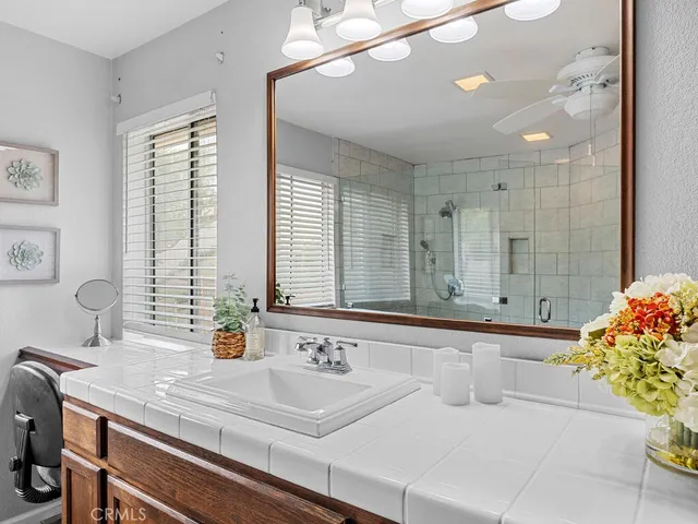 a bathroom with a sink a large mirror and a bathtub next to a window