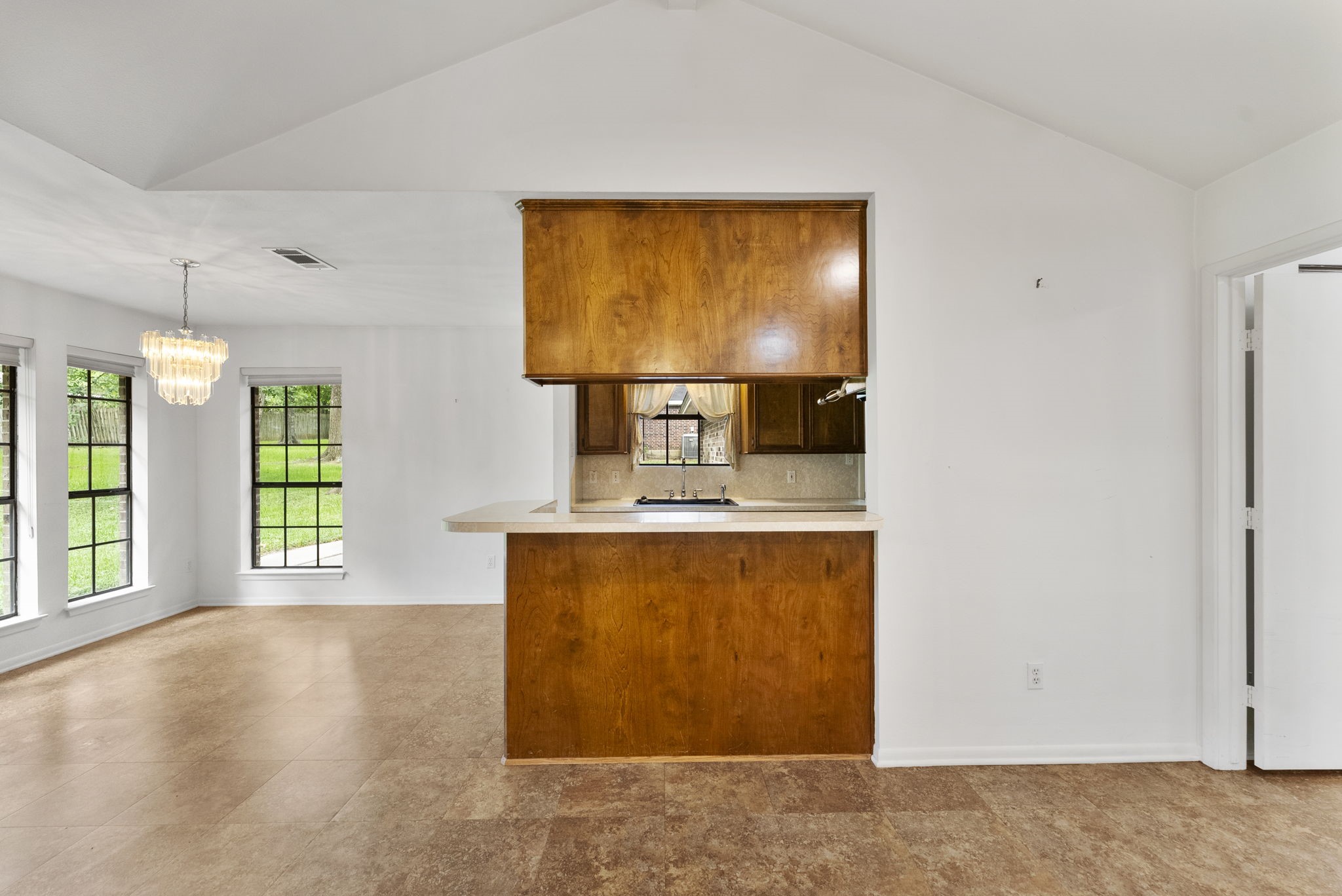 202 Sunset Boulevard Conroe, TX 77303 - Photo 13 of 50 This inviting space features a charming breakfast bar, perfect for casual dining, and flows seamlessly into a bright living area with large windows and elegant lighting, offering a warm and welcoming atmosphere.