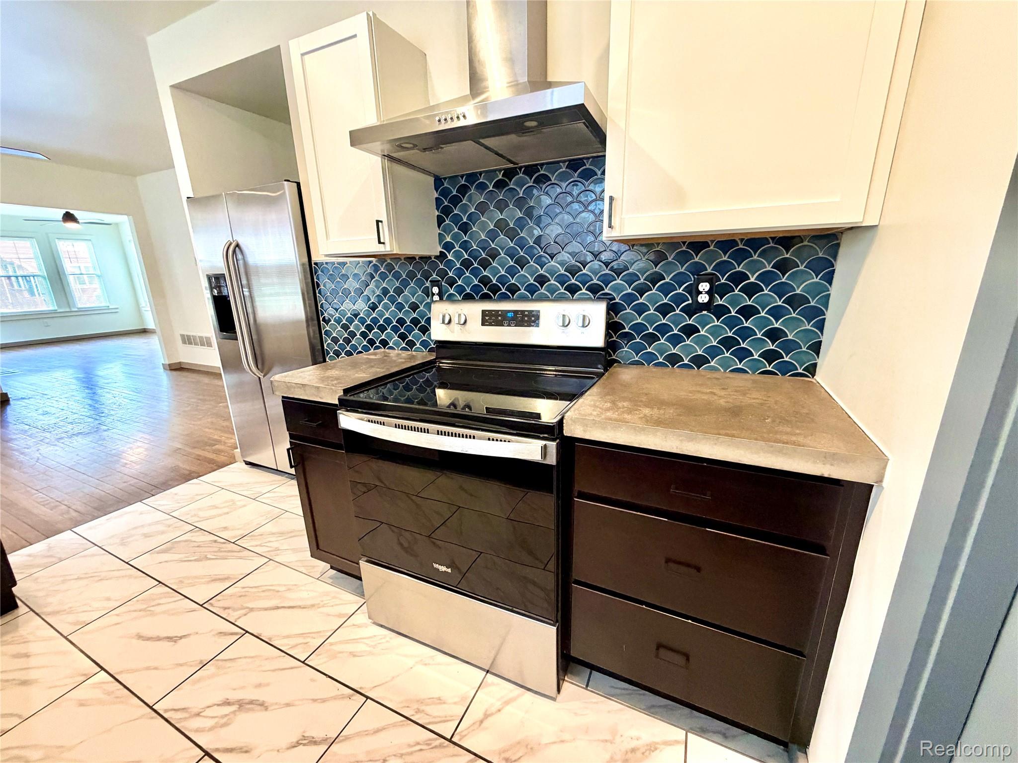 2045 Calvert Avenue Detroit, MI 48206 - Photo 4 of 41 Dual tone kitchen with stainless steel appliances, dual tone cabinetry, light countertops, light marble finish floors, and backsplash