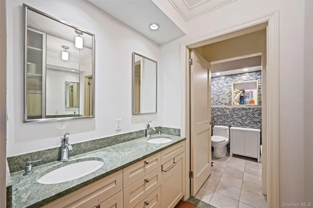 a bathroom with a granite countertop sink mirror and a toilet