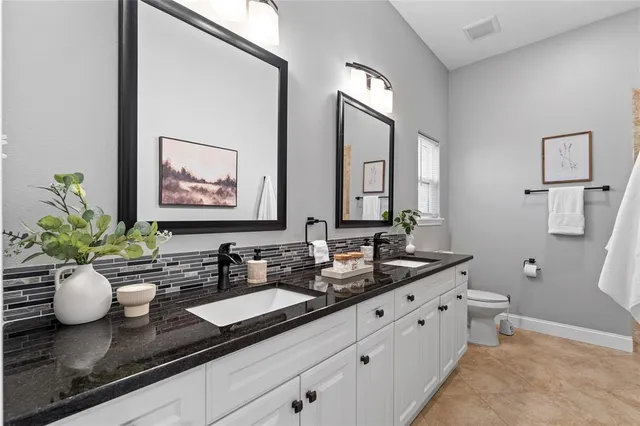 a bathroom with a granite countertop sink a toilet and mirror