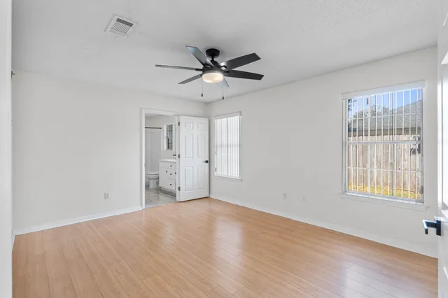 a view of an empty room with a window and wooden floor