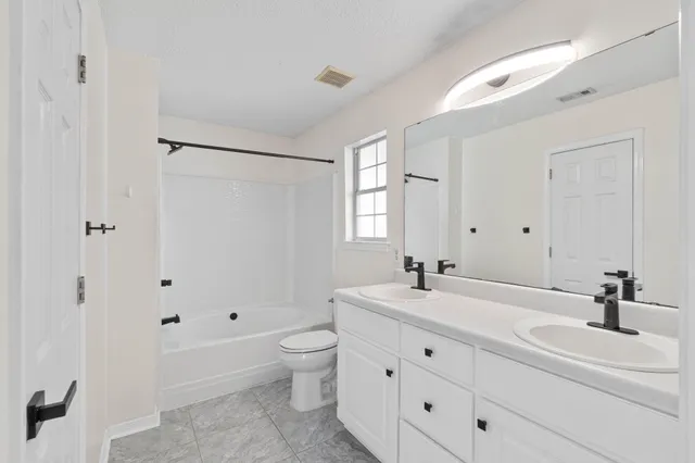 a bathroom with a double vanity sink a mirror and a bathtub