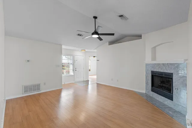 a view of an empty room with wooden floor fireplace and a window