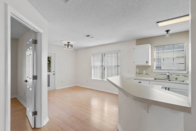 a large white kitchen with kitchen island a sink stainless steel appliances and cabinets