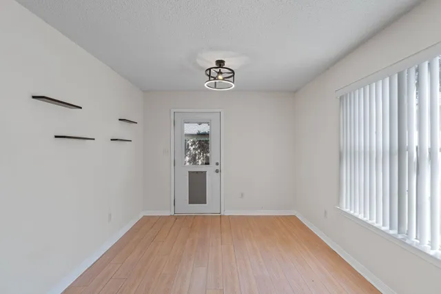 an empty room with wooden floor closet and windows