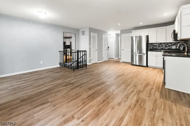 a view of an empty room with kitchen and a window
