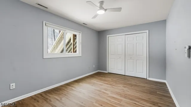 a view of empty room with wooden floor and fan