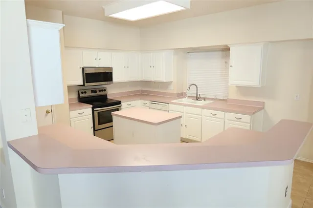 a kitchen with stainless steel appliances a stove a sink a microwave and white cabinets