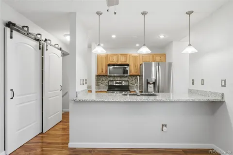 a view of a kitchen with a refrigerator a sink and a wooden floor