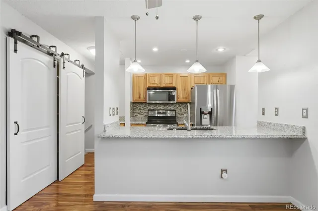 a view of a kitchen with a refrigerator a sink and a wooden floor
