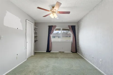 an empty room with windows and fan