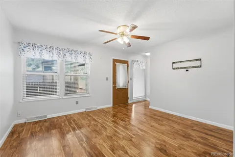 a view of an empty room with wooden floor and a window