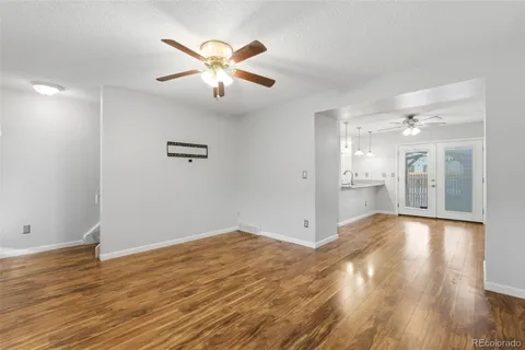 a view of an empty room with wooden floor and a ceiling fan