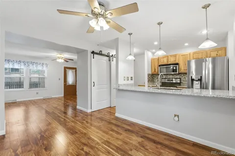a open kitchen with stainless steel appliances granite countertop a refrigerator a oven and a wooden floor