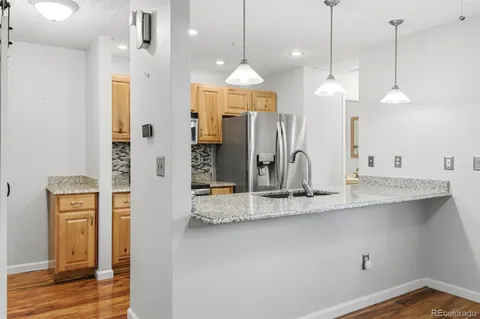 a view of a kitchen with a refrigerator a sink and wooden floor