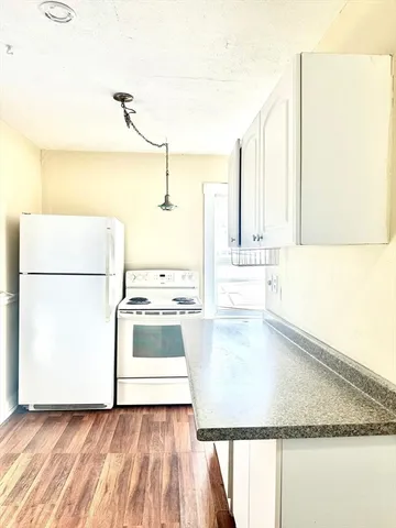 a view of a kitchen with kitchen island a sink wooden floor and a dining table