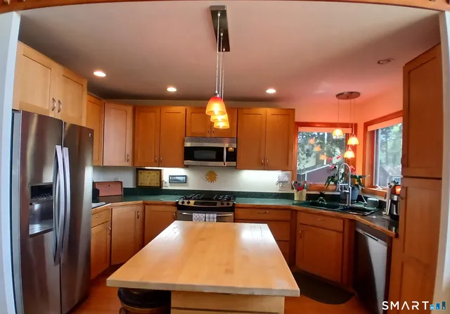 a kitchen with kitchen island granite countertop a sink a counter top space stainless steel appliances and cabinets