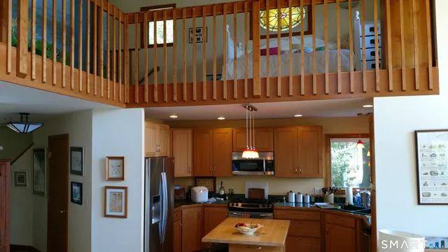 a kitchen with stainless steel appliances kitchen island granite countertop a refrigerator a stove and a sink with wooden floor