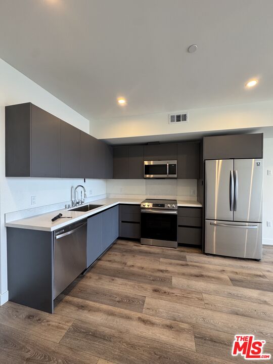 919 South Harvard Boulevard, Unit 403 Los Angeles, CA 90006 - Photo 3 of 9 a large kitchen with stainless steel appliances wooden cabinets and a counter top space