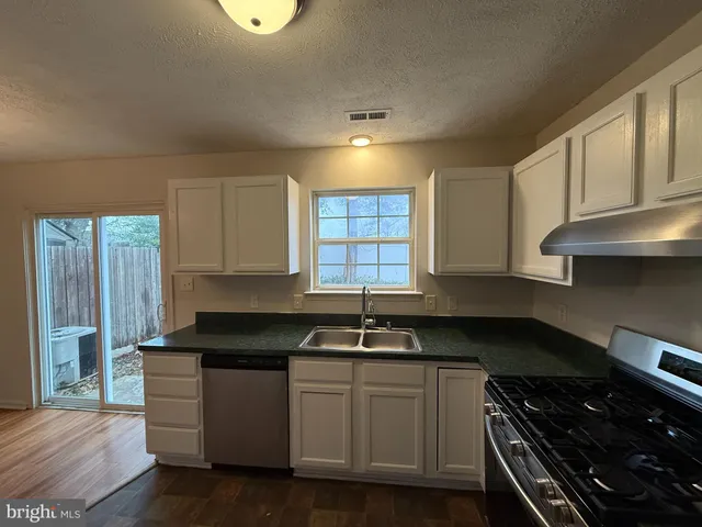 a kitchen with granite countertop a sink a stove and cabinets
