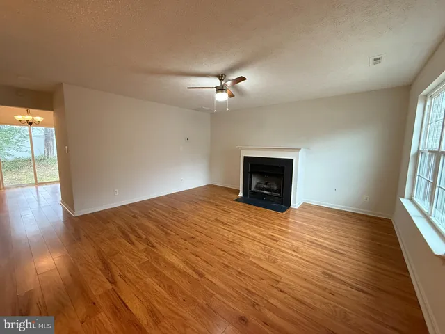 an empty room with wooden floor fireplace and windows