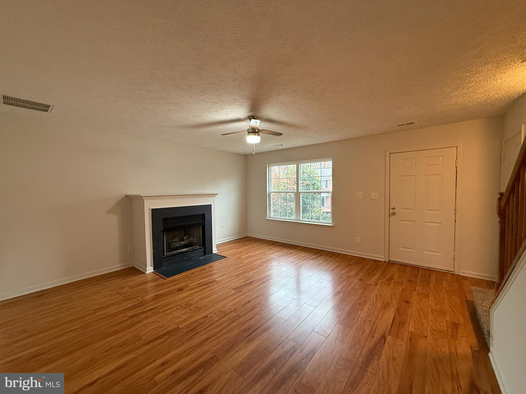 4345 Normandy Court Fredericksburg, VA 22408 - Photo 6 of 44 an empty room with wooden floor fireplace and windows