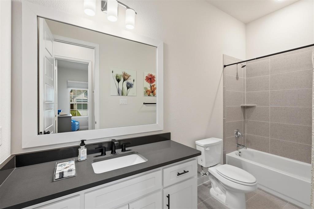 11116 Emory Oak Ridge Flower Mound, TX 76226 - Photo 23 of 40 a bathroom with a granite countertop sink a toilet a mirror and shower