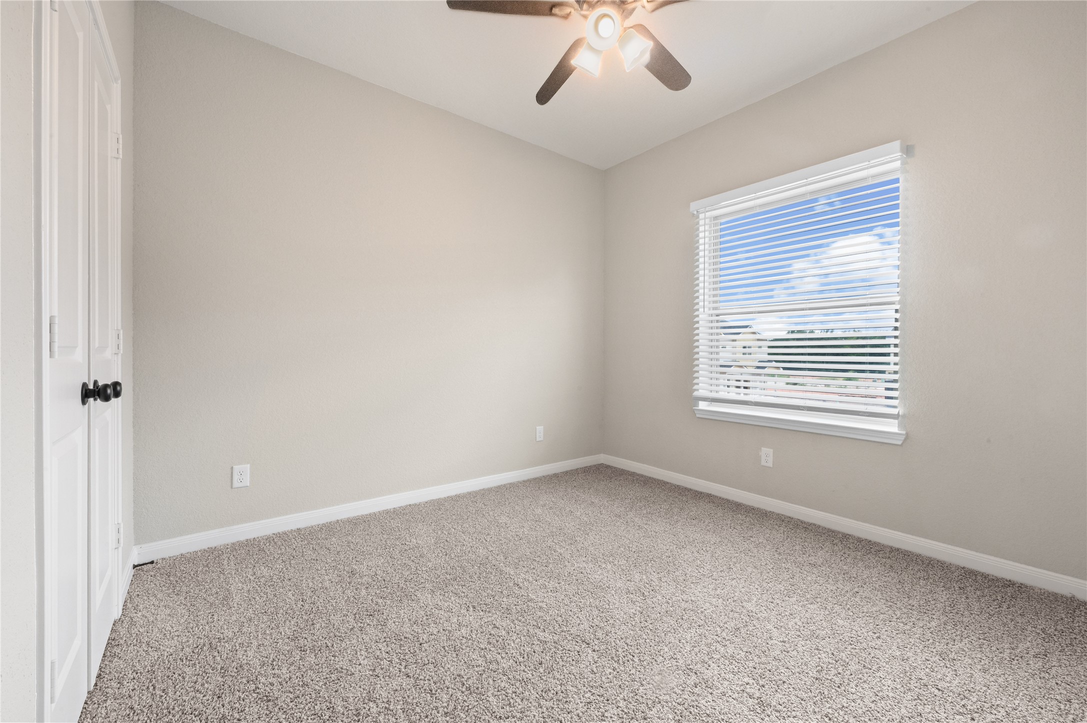 14010 Longstreet Road, Unit 2 Willis, TX 77318 - Photo 8 of 29 This photo showcases a cozy, carpeted bedroom with neutral walls, a ceiling fan, and a window with blinds that lets in natural light. Perfect for a small office or guest room.
