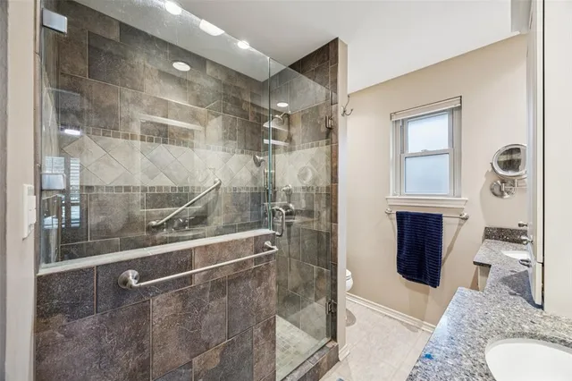 a bathroom with a granite countertop bathtub shower and mirror