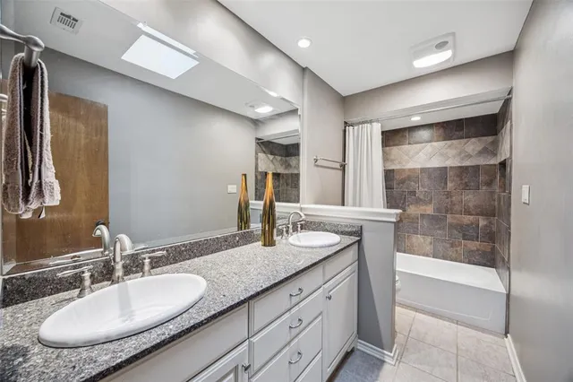 a bathroom with a granite countertop sink a mirror and shower