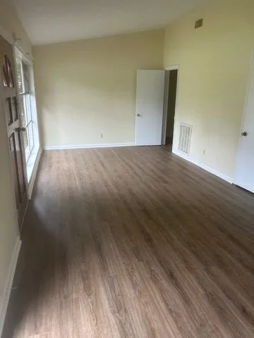 an empty room with wooden floor and entrance