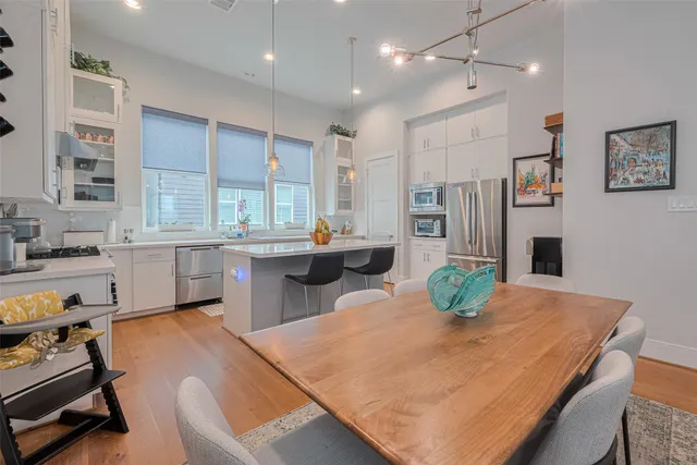 a kitchen with stainless steel appliances granite countertop a sink a stove a dining table and chairs