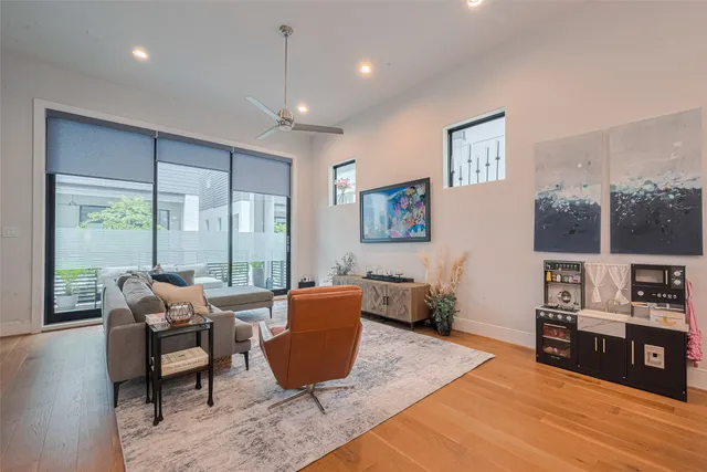 a living room with furniture a large window and wooden floor