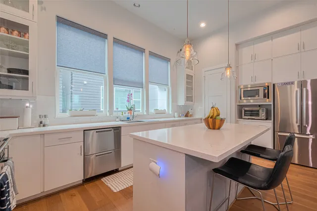 a kitchen with stainless steel appliances granite countertop a sink a stove a refrigerator and island with wooden floor