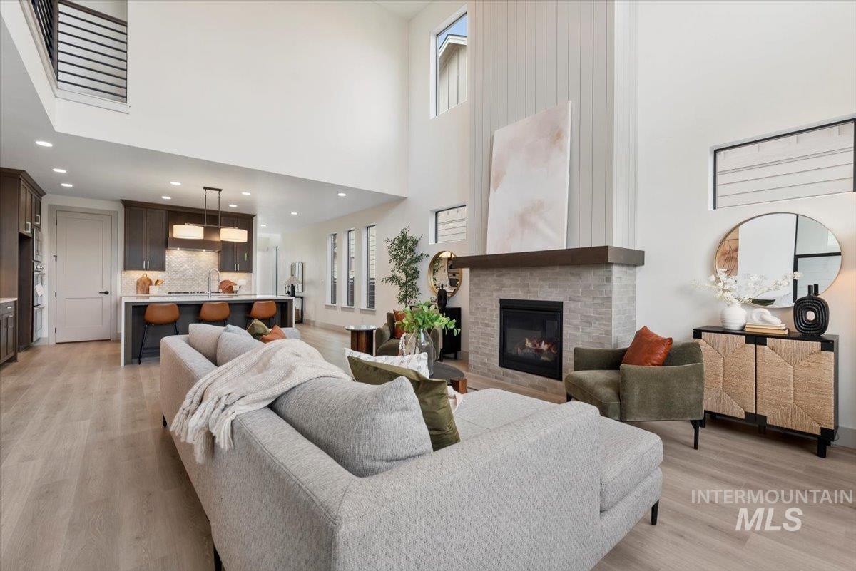 7580 West Old School Street, Unit FREMONT Meridian, ID 83646 - Photo 9 of 28 Living room featuring light wood finished floors, a brick fireplace, a high ceiling, and recessed lighting