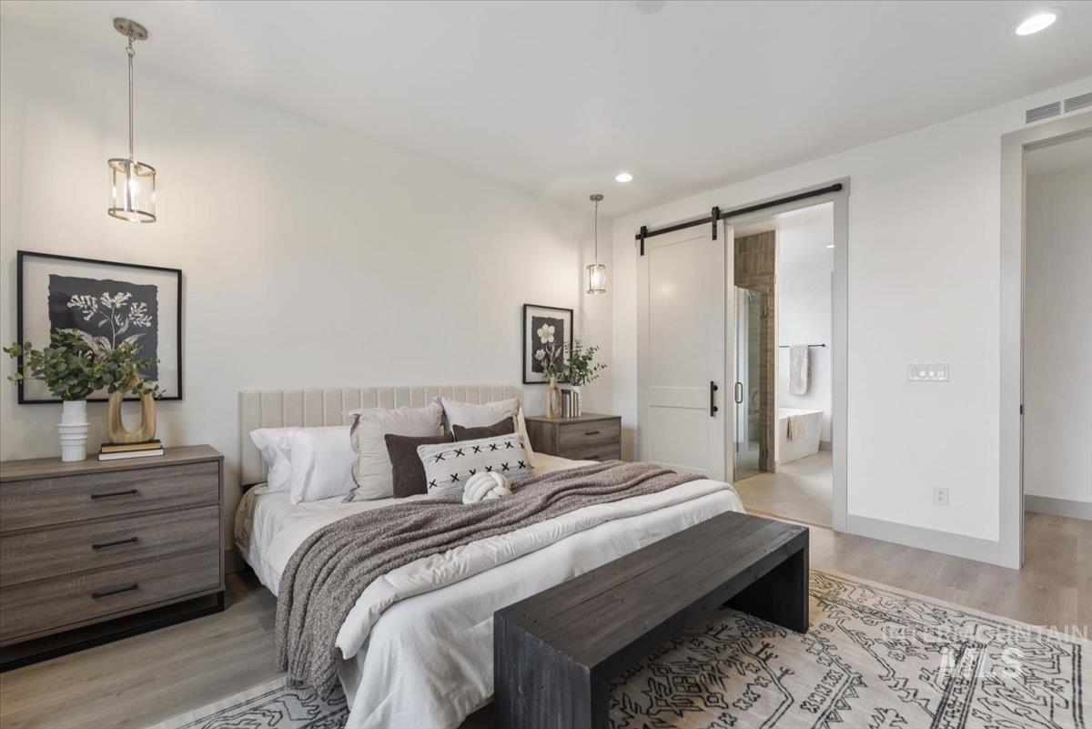 7580 West Old School Street, Unit FREMONT Meridian, ID 83646 - Photo 14 of 28 Bedroom with a barn door, light wood-type flooring, recessed lighting, and ensuite bathroom