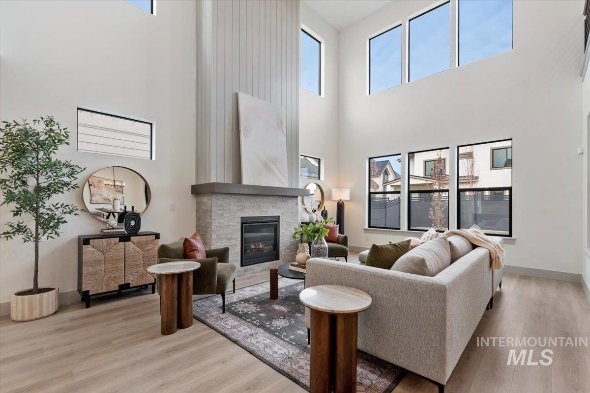 7580 West Old School Street, Unit FREMONT Meridian, ID 83646 - Photo 8 of 28 Living area with light wood finished floors, a glass covered fireplace, plenty of natural light, and a high ceiling