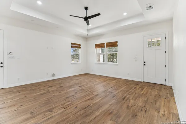 a view of empty room with wooden floor and fan