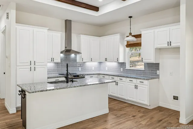 a kitchen with stainless steel appliances granite countertop a sink stove and white cabinets with wooden floor