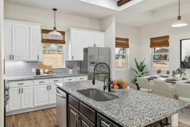 a kitchen with granite countertop a sink a counter space appliances and cabinets