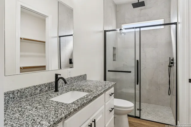 a bathroom with a granite countertop sink toilet and shower