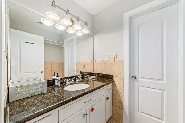 a bathroom with a granite countertop sink a light fixture and a mirror