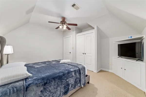 a spacious bedroom with a bed a flat screen tv and a chandelier