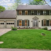 a front view of a house with a yard and trees