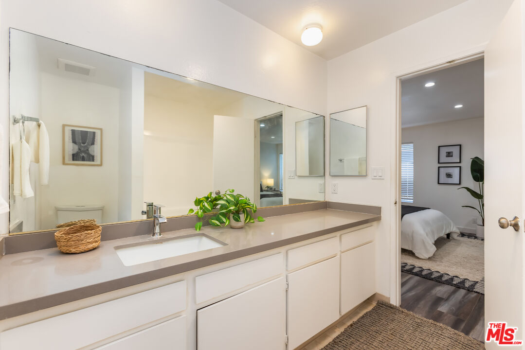 11701 Texas Avenue, Unit 306 Los Angeles, CA 90025 - Photo 32 of 42 a bathroom with a granite countertop sink and a mirror