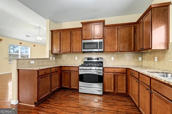 a kitchen with stainless steel appliances granite countertop a stove a sink and a microwave