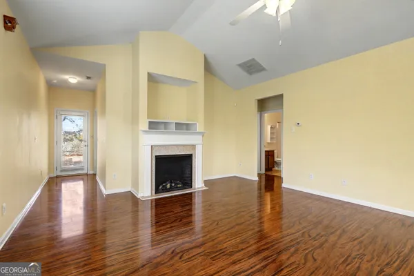 a view of an empty room with wooden floor and a fireplace