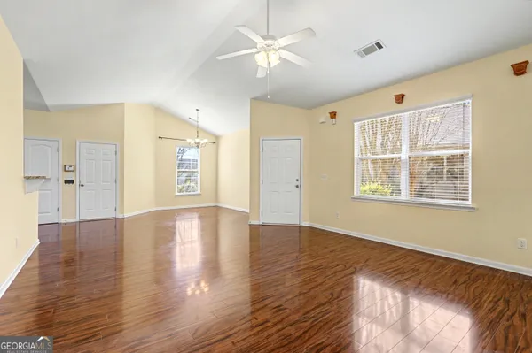 a view of an empty room with window and wooden floor
