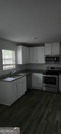 a kitchen with granite countertop a sink cabinets and stainless steel appliances